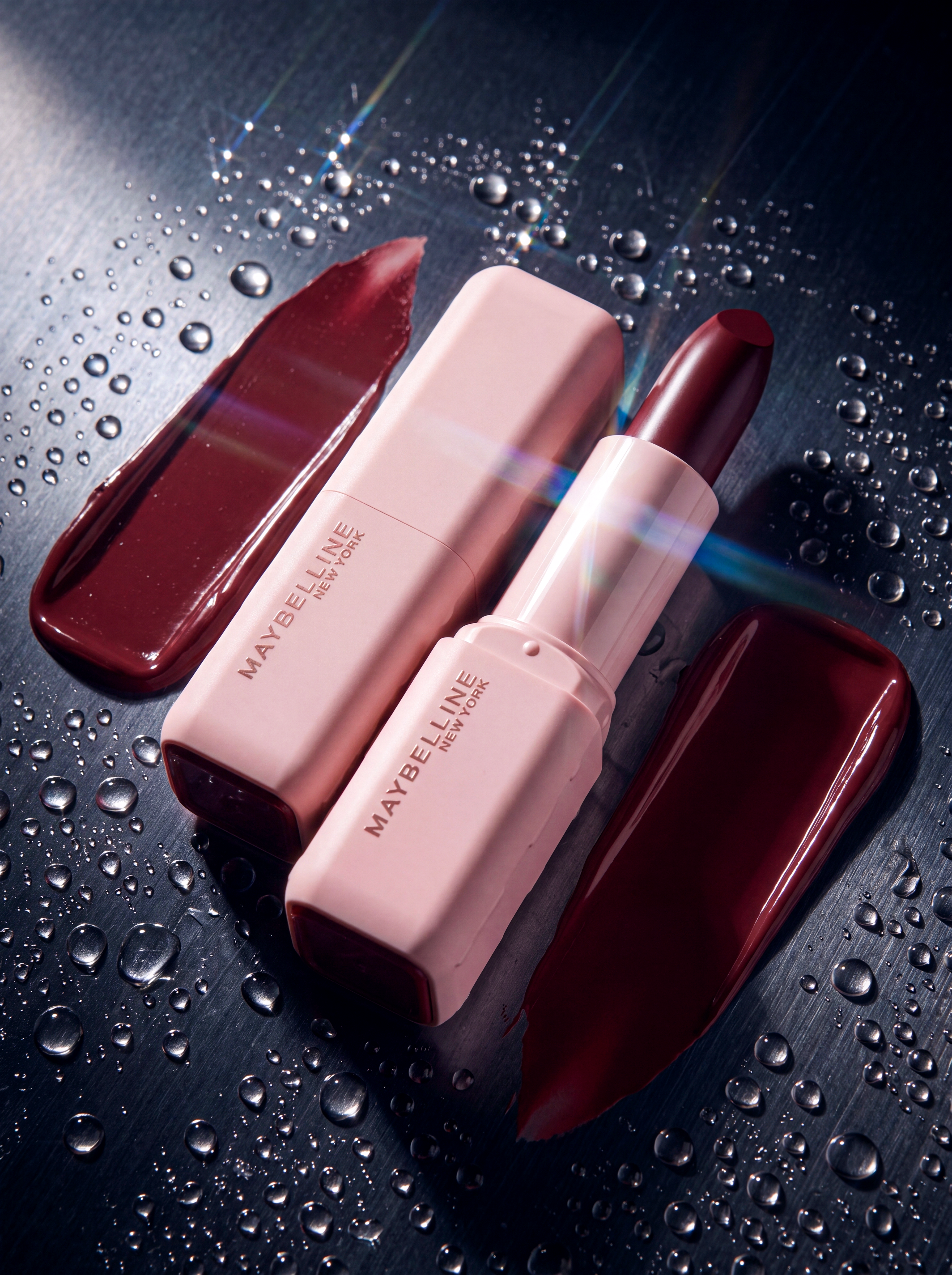 Product still life with red cosmetic texture, pale pink packaging, water drops and reflective metal